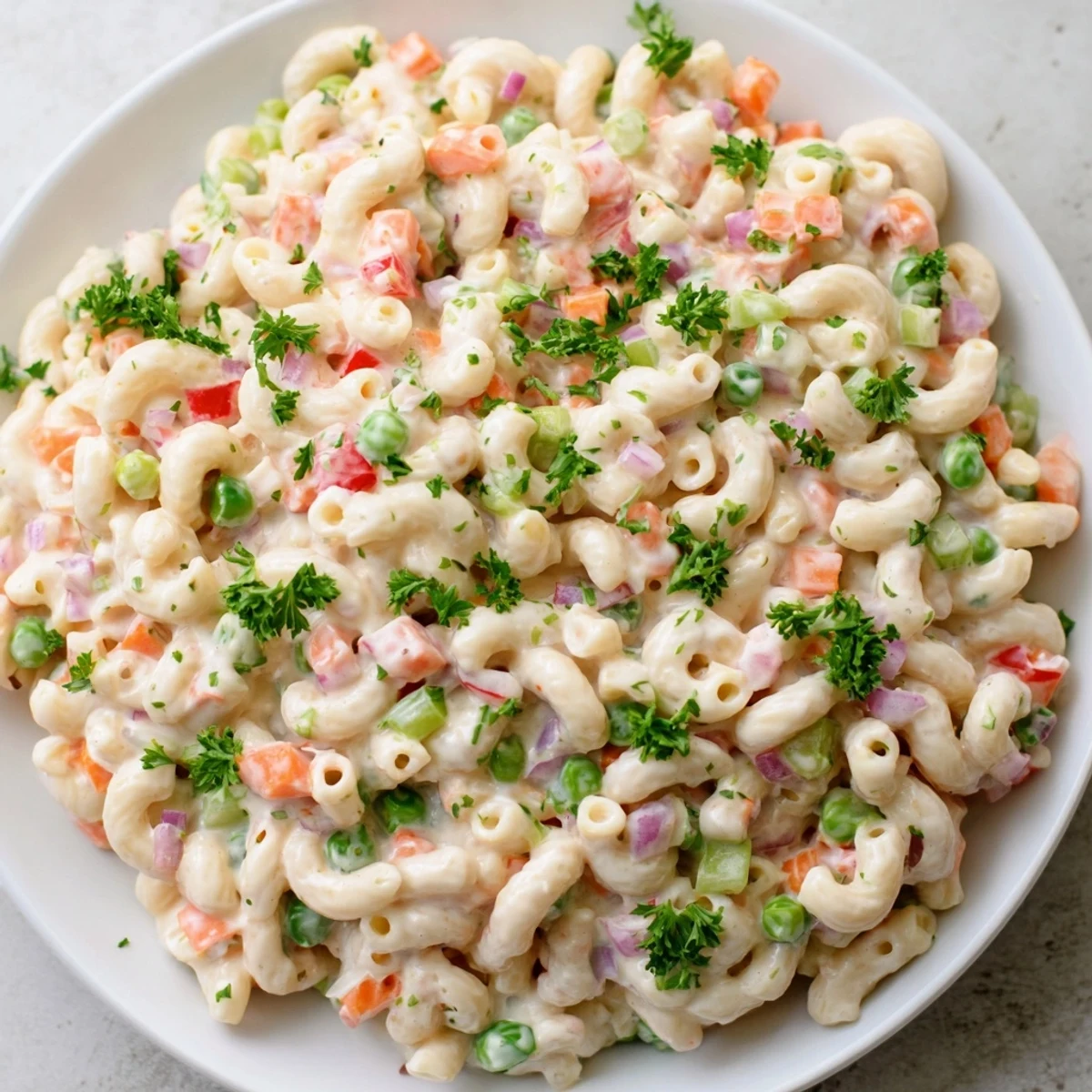 Creamy macaroni salad, chilled and ready for a picnic, with vibrant red bell peppers.