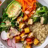This Buddha bowl displays a delicious contrast with fluffy grains, fresh toppings, and grilled tofu.