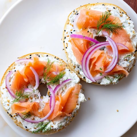 Warm, toasted bagel with cream cheese, invitingly topped with fresh tomato and herbs.