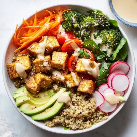 A colorful Buddha bowl filled with vibrant vegetables, tofu, and creamy tahini dressing.