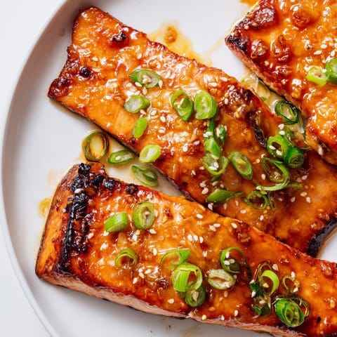 A close-up shot of flaky Honey Garlic Salmon served atop fluffy white rice and veggies.