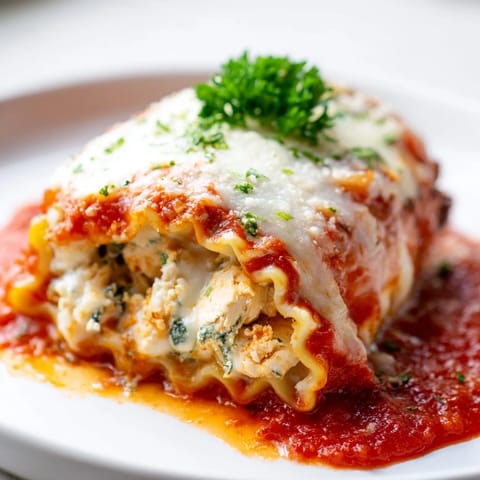 Tender Chicken and Spinach Lasagna Rolls stuffed with creamy ricotta, spinach, and melted mozzarella on a white plate.