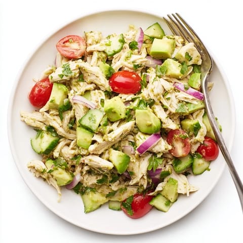 Homemade Avocado Chicken Salad in a clear glass bowl, garnished with cilantro and served alongside crisp lettuce leaves for wrapping.