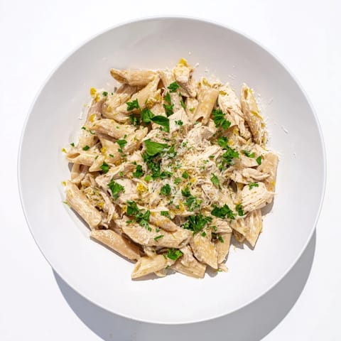 Savory Roasted Garlic Chicken Penne topped with extra Parmesan and red pepper flakes for heat.