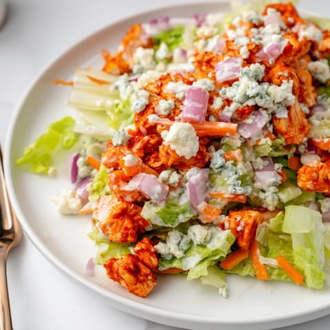 Hearty Buffalo Chicken Chopped Salad is artfully arranged on a white plate, ready for a satisfying gluten-free lunch.