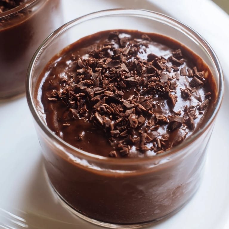 Dark, glossy chocolate pudding in elegant serving glasses, perfect for a special treat at home.