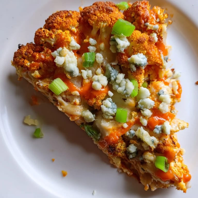 Buffalo Cauliflower Pizza fresh from the oven, topped with bubbly cheese, celery slices, and vibrant green onions for a tangy bite.  