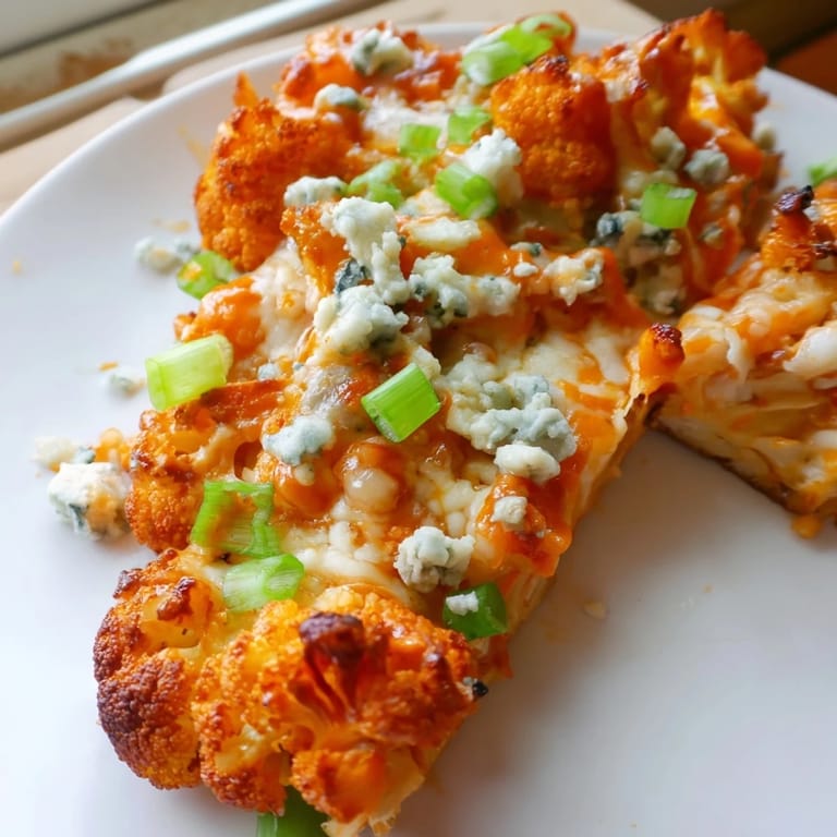 Overhead view of a whole Buffalo Cauliflower Pizza, with drizzled buffalo sauce, melted mozzarella, and chopped parsley garnish.