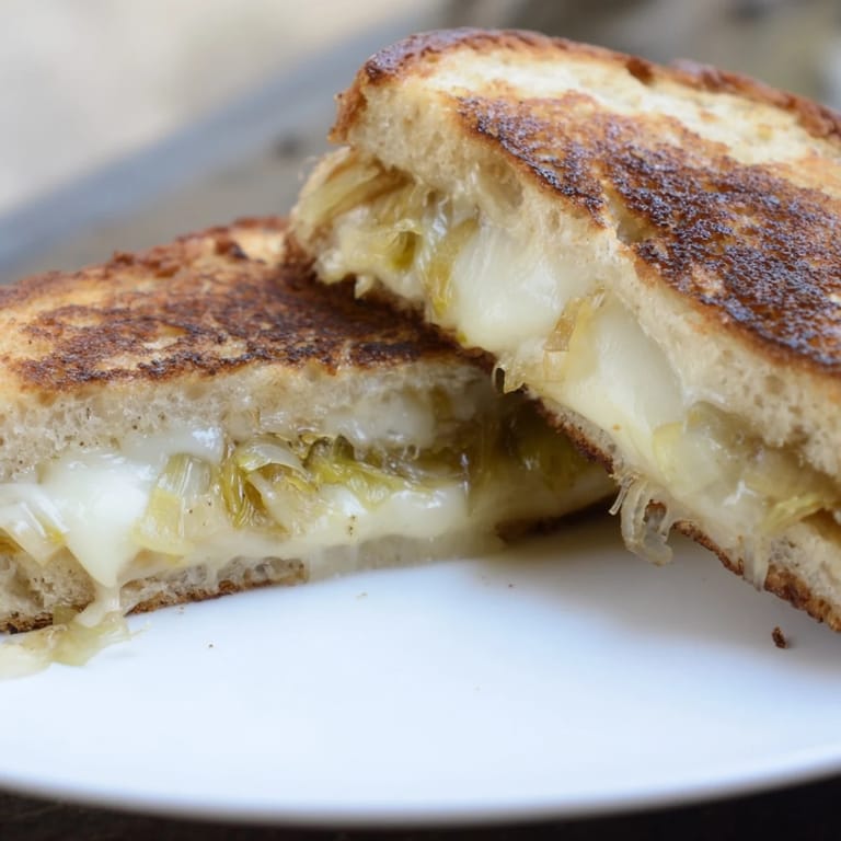 Toasted Havarti & Caramelized Leek Grilled Cheese beside a bowl of tomato soup.