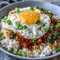 Spicy fermented cabbage kimchi fried rice bowl with a sunny-side-up egg.